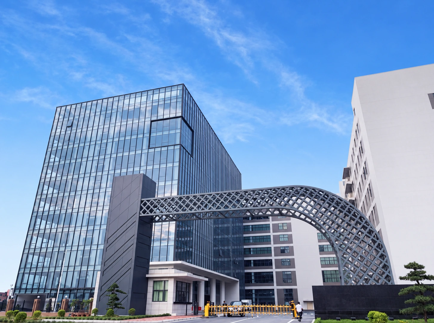 Glass-fronted factory building with a curved lattice entrance arch